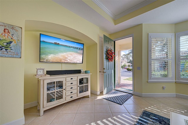 entryway featuring light tile patterned floors, crown molding, and a raised ceiling