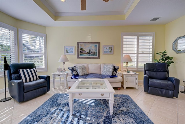 living room with crown molding, a tray ceiling, and light tile patterned floors