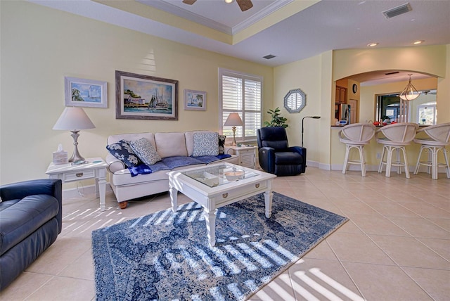 living room featuring crown molding, ceiling fan, a tray ceiling, and light tile patterned floors