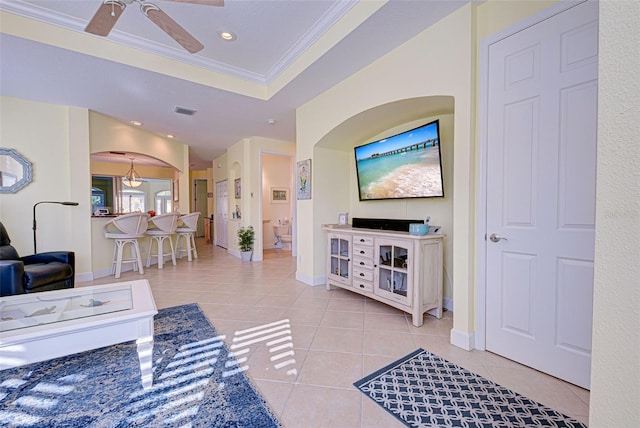 living room with crown molding, light tile patterned floors, ceiling fan, and a tray ceiling