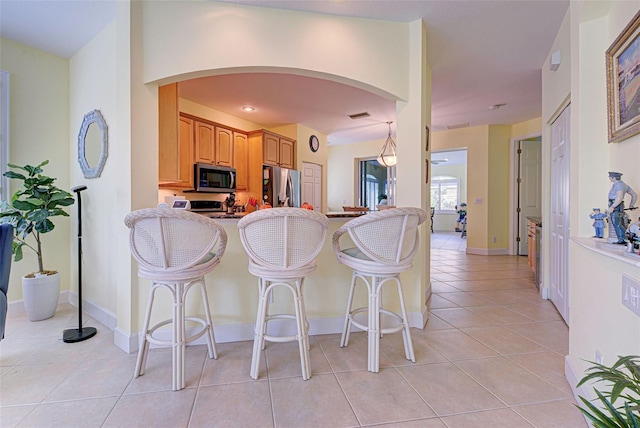 kitchen featuring light tile patterned flooring, appliances with stainless steel finishes, and a breakfast bar area