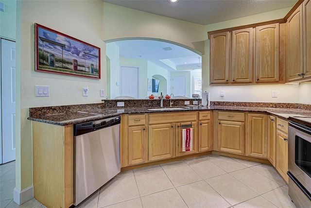 kitchen with sink, light tile patterned flooring, dark stone counters, and appliances with stainless steel finishes