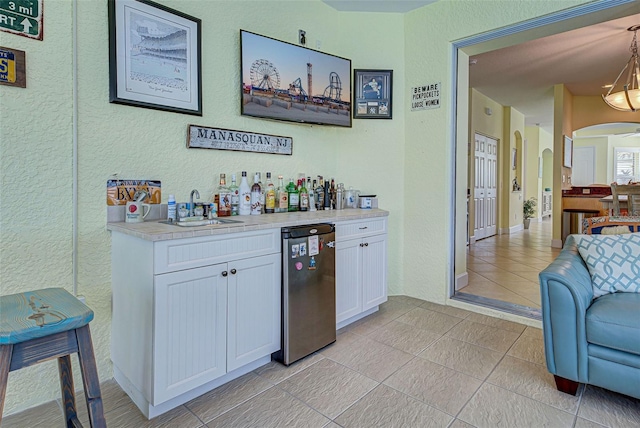 bar with light tile patterned flooring, sink, white cabinetry, dishwasher, and pendant lighting