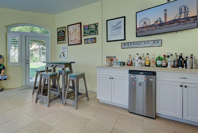 bar featuring white cabinetry, dishwasher, and light tile patterned flooring