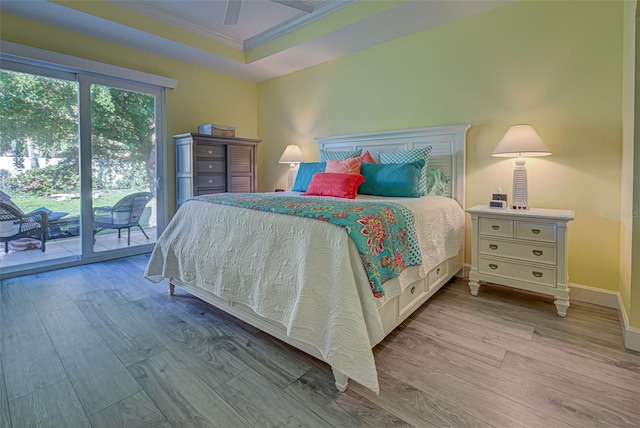 bedroom with light wood-type flooring, access to outside, ornamental molding, a raised ceiling, and ceiling fan