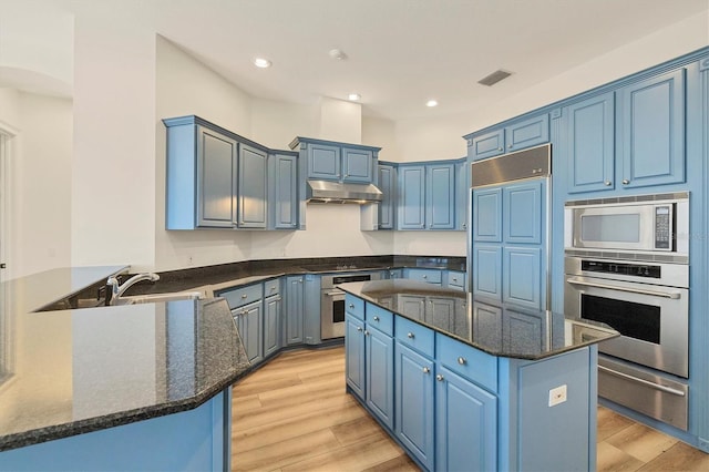 kitchen featuring appliances with stainless steel finishes, blue cabinetry, light wood-type flooring, and kitchen peninsula