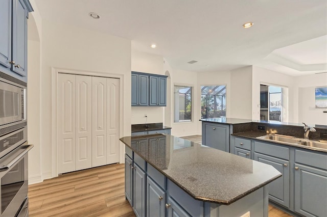 kitchen featuring sink, light hardwood / wood-style flooring, gray cabinets, appliances with stainless steel finishes, and a kitchen island