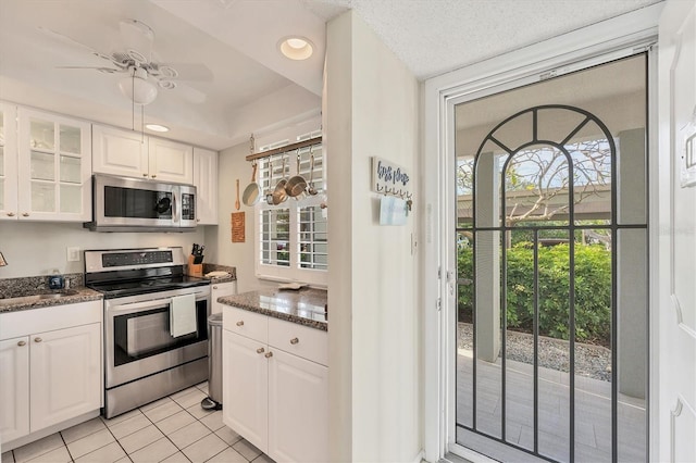 kitchen featuring white cabinetry, light tile patterned floors, stainless steel appliances, and dark stone countertops