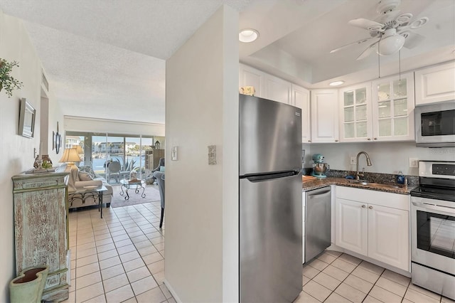 kitchen featuring appliances with stainless steel finishes, sink, light tile patterned floors, and white cabinets