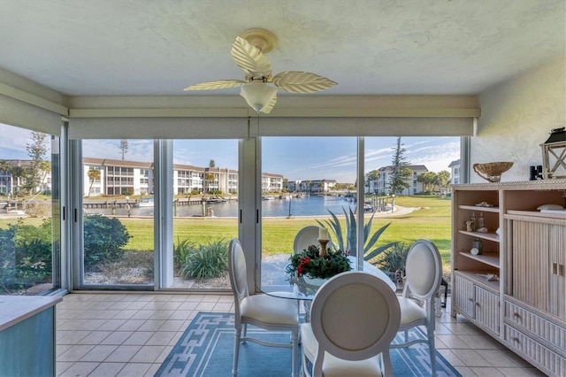 unfurnished sunroom with ceiling fan and a water view