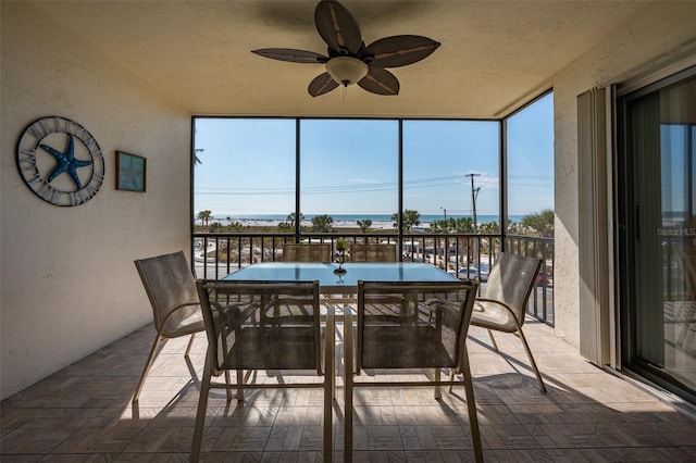 sunroom / solarium featuring a water view and ceiling fan