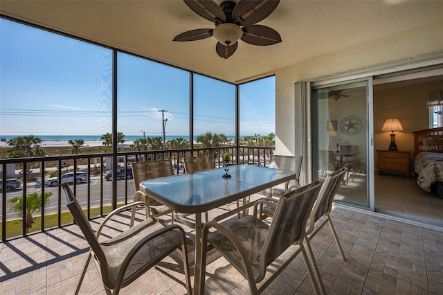 sunroom / solarium featuring a wealth of natural light, ceiling fan, and a water view