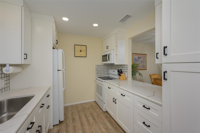 kitchen featuring white cabinetry, white appliances, light stone countertops, and light wood-type flooring