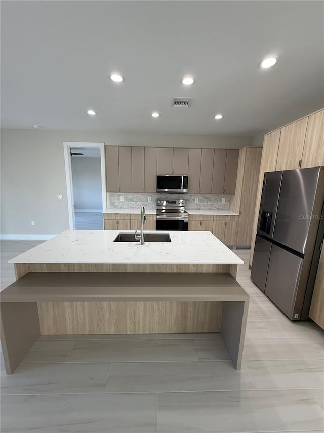 kitchen featuring tasteful backsplash, stainless steel appliances, sink, and a kitchen island with sink