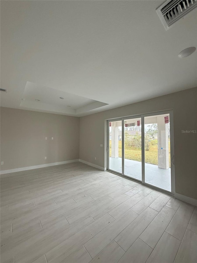 spare room with light hardwood / wood-style flooring and a tray ceiling