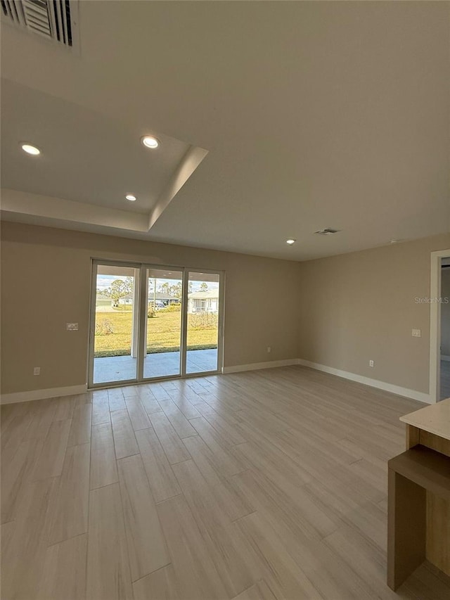 empty room with light hardwood / wood-style flooring and a raised ceiling