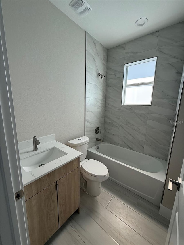 full bathroom featuring vanity, tiled shower / bath combo, and toilet