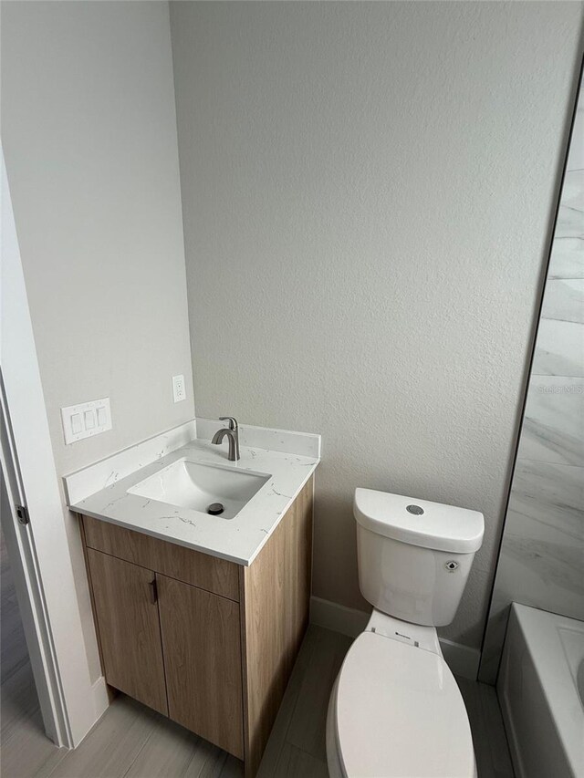 bathroom featuring vanity, hardwood / wood-style floors, and toilet