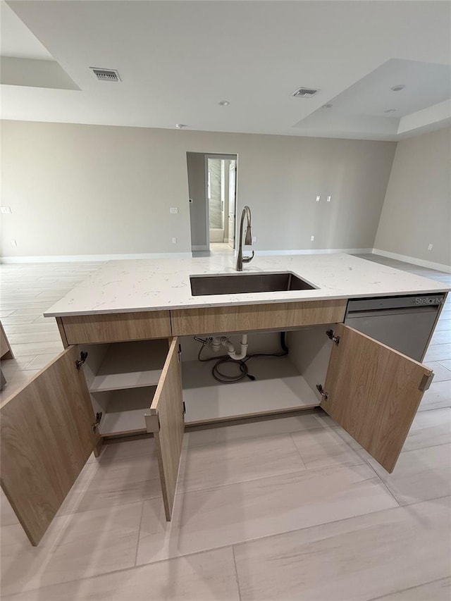 kitchen featuring light stone counters, sink, and dishwasher