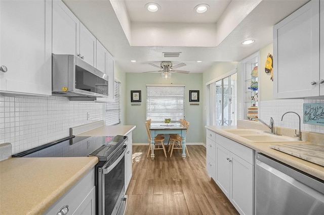 kitchen featuring sink, a raised ceiling, white cabinets, and appliances with stainless steel finishes