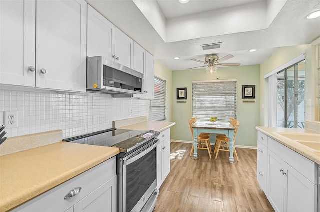 kitchen featuring white cabinetry, sink, decorative backsplash, stainless steel appliances, and light hardwood / wood-style flooring