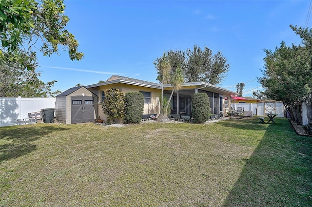 rear view of property with a shed, a lawn, and a sunroom