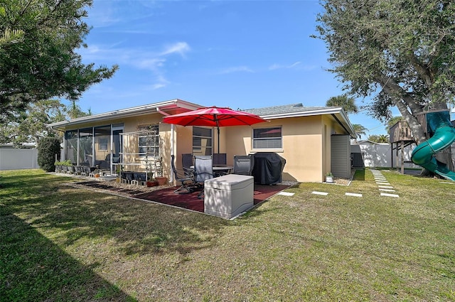 back of house featuring a playground, a sunroom, and a yard