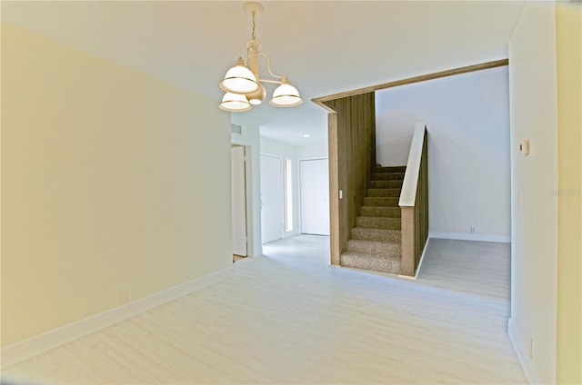 empty room with light hardwood / wood-style floors and a notable chandelier