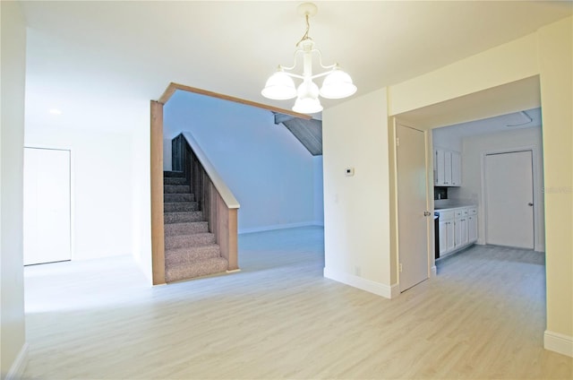 unfurnished dining area with a notable chandelier and light wood-type flooring