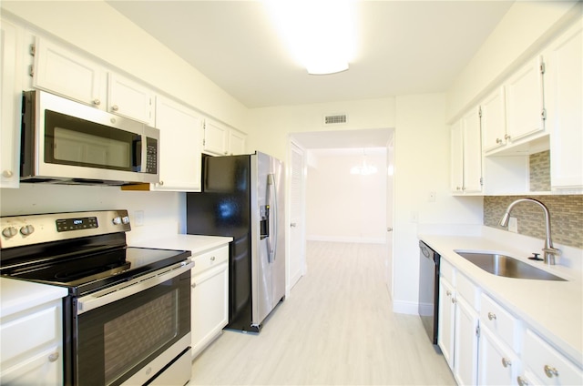 kitchen featuring sink, white cabinetry, tasteful backsplash, light hardwood / wood-style flooring, and stainless steel appliances