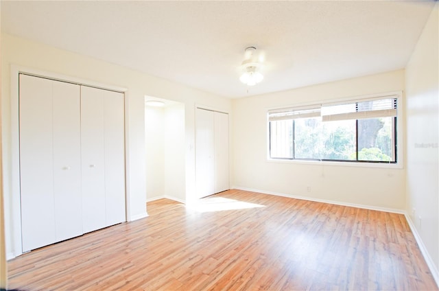 unfurnished bedroom featuring light hardwood / wood-style floors and two closets