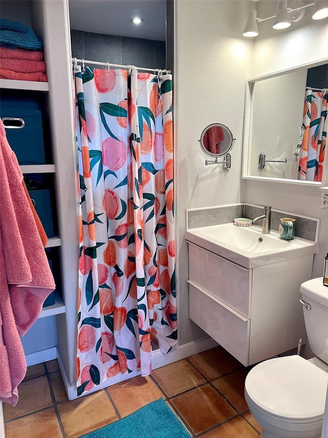 bathroom with vanity, tile patterned flooring, toilet, and walk in shower