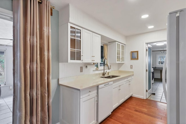 kitchen featuring white cabinetry, sink, white appliances, and light hardwood / wood-style floors