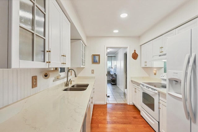 kitchen featuring sink, white cabinets, light hardwood / wood-style floors, light stone countertops, and white appliances