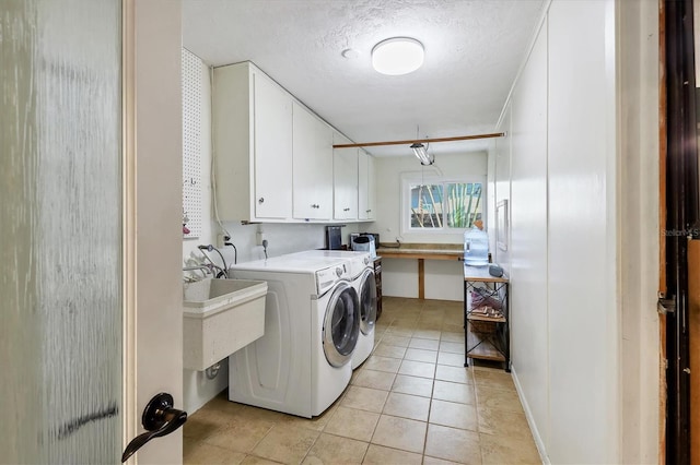 laundry area featuring cabinets, light tile patterned flooring, a textured ceiling, and independent washer and dryer