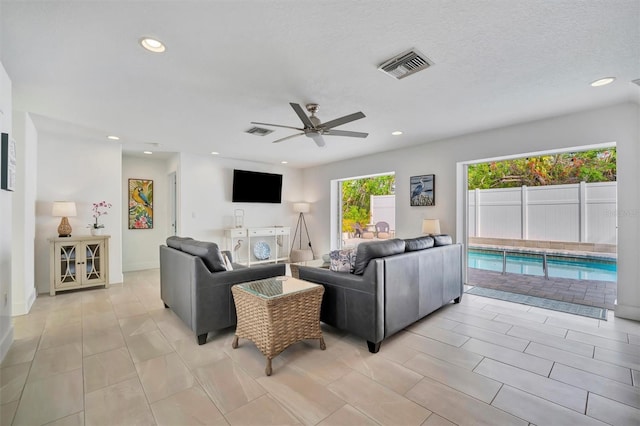 living room with ceiling fan, light tile patterned floors, and a textured ceiling