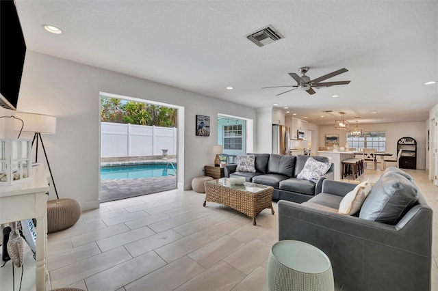 living room with ceiling fan and a textured ceiling