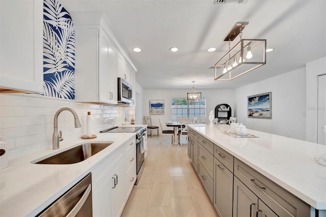 kitchen featuring sink, white cabinetry, hanging light fixtures, stainless steel appliances, and decorative backsplash