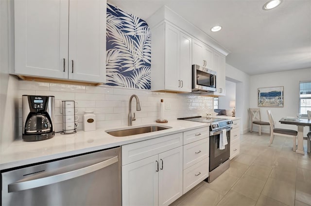 kitchen with stainless steel appliances, sink, white cabinets, and decorative backsplash