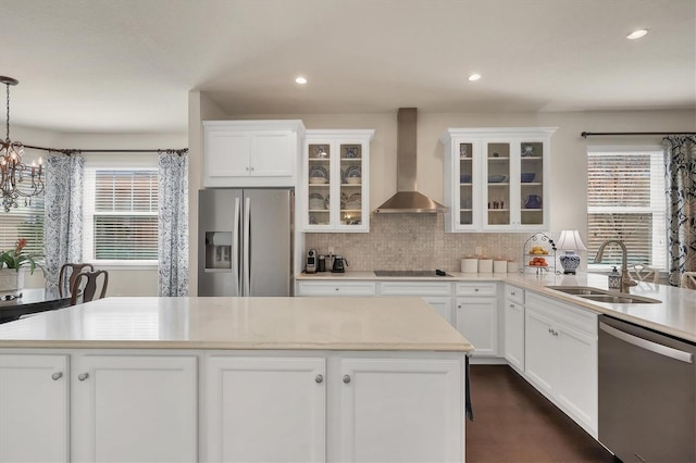 kitchen featuring appliances with stainless steel finishes, decorative light fixtures, white cabinetry, sink, and wall chimney range hood