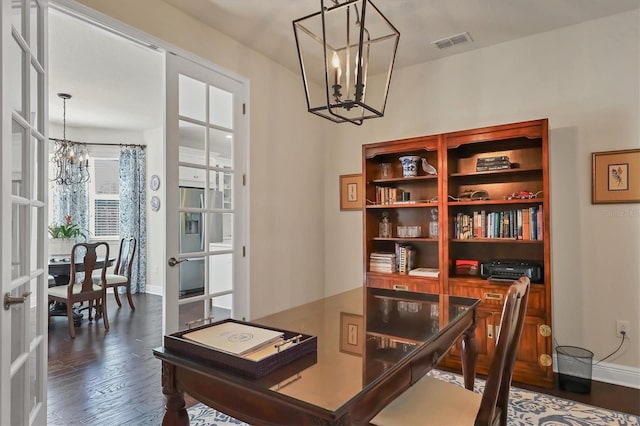 home office with dark wood-type flooring, a chandelier, and french doors