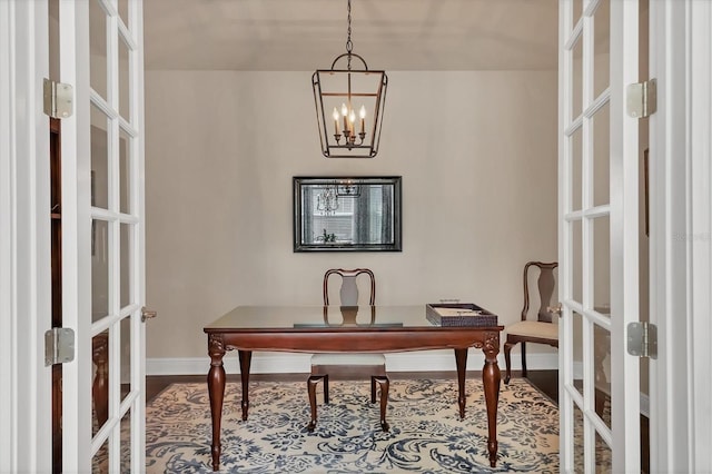 home office with hardwood / wood-style flooring, an inviting chandelier, and french doors