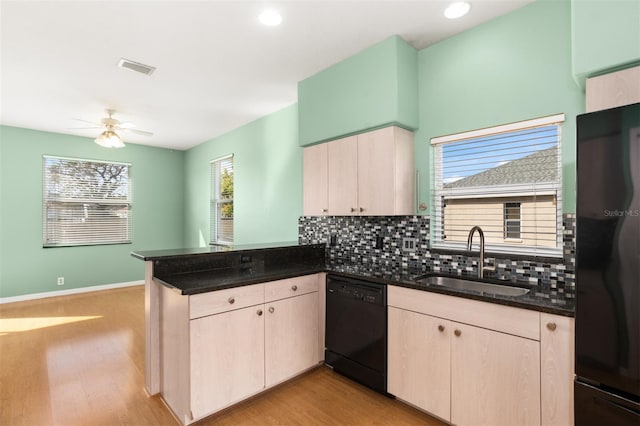 kitchen with dark stone counters, kitchen peninsula, sink, and black appliances