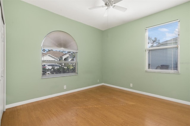 spare room featuring a healthy amount of sunlight, ceiling fan, and wood-type flooring