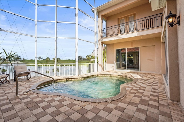 view of swimming pool featuring glass enclosure, a water view, and a patio