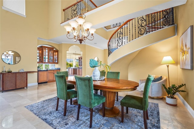 dining room featuring crown molding, a towering ceiling, baseboards, and an inviting chandelier