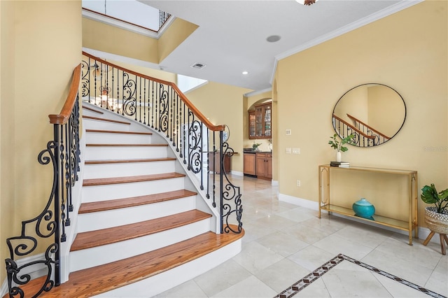 stairs featuring a skylight, baseboards, visible vents, crown molding, and recessed lighting