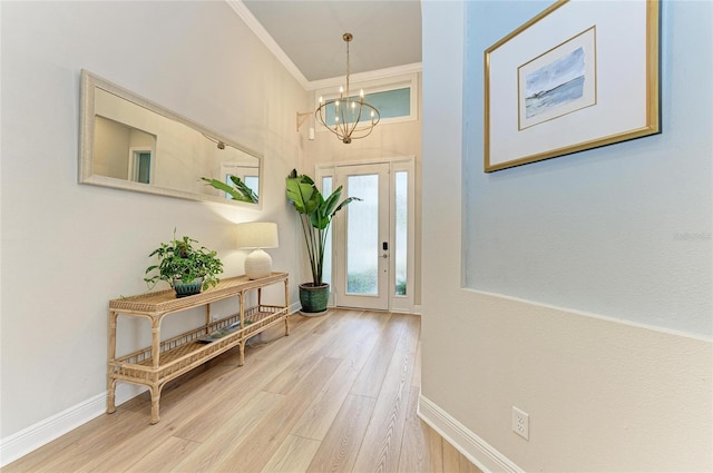 foyer entrance featuring hardwood / wood-style flooring, ornamental molding, and a notable chandelier