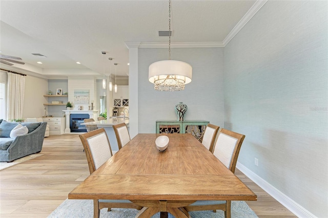 dining space with crown molding and light hardwood / wood-style flooring