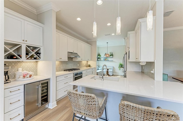 kitchen with sink, white cabinetry, a kitchen bar, decorative light fixtures, and kitchen peninsula